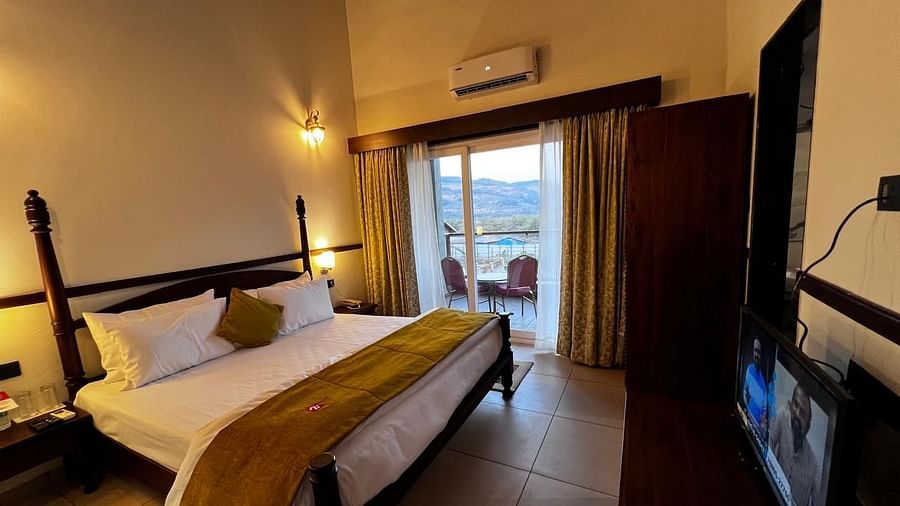 Royal Suite room featuring a large bed with plush bedding and a wide window at Mastiff Grand La Villae Resort, Lonavala